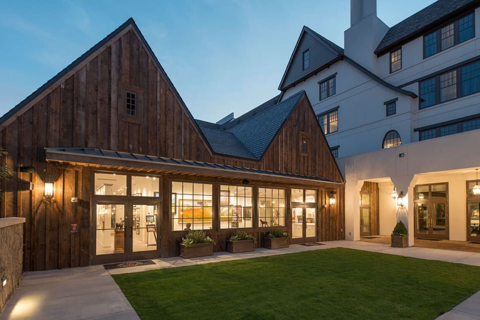 Modern gallery building with wooden facade and glass windows at dusk