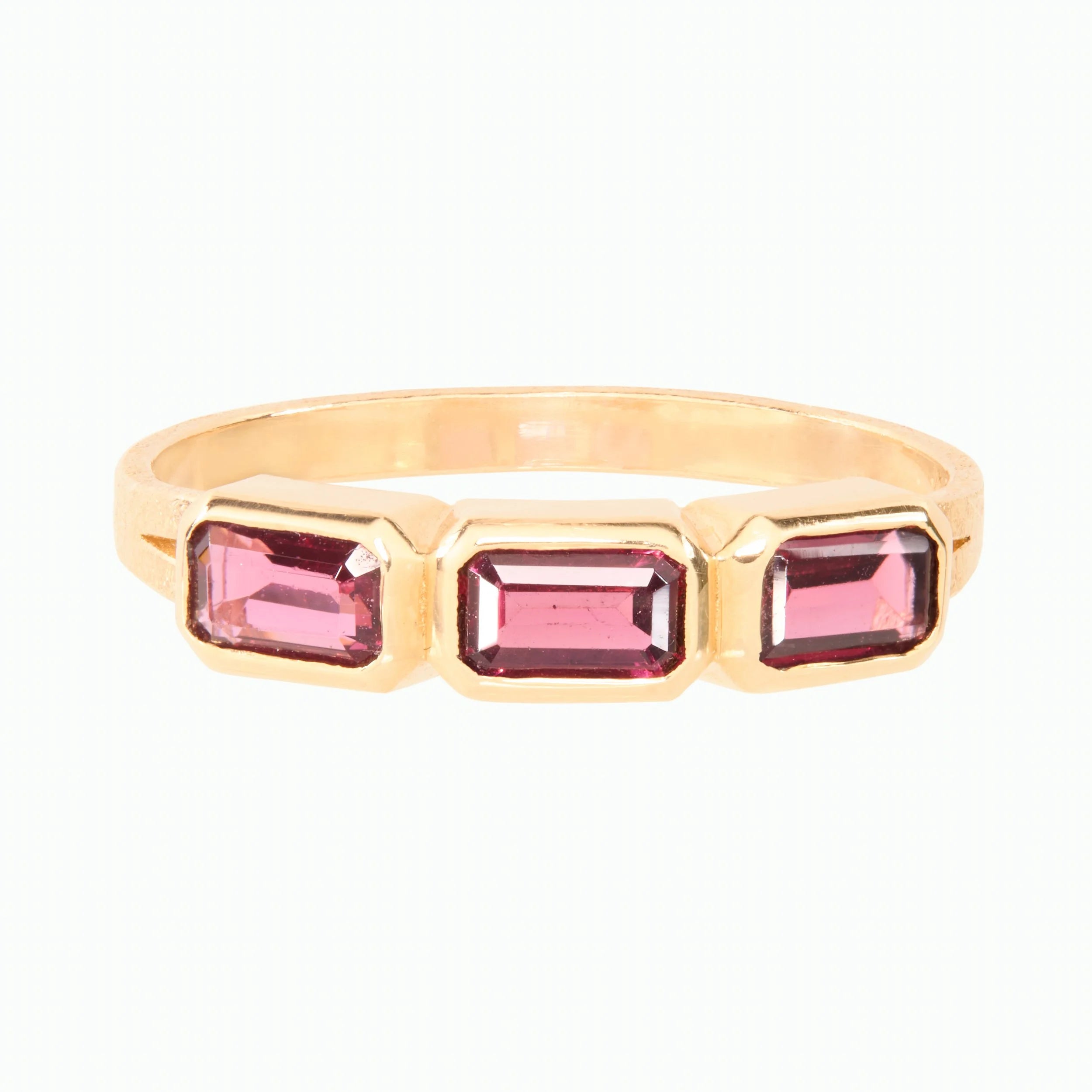 Gold ring with three purple gemstones on a white background