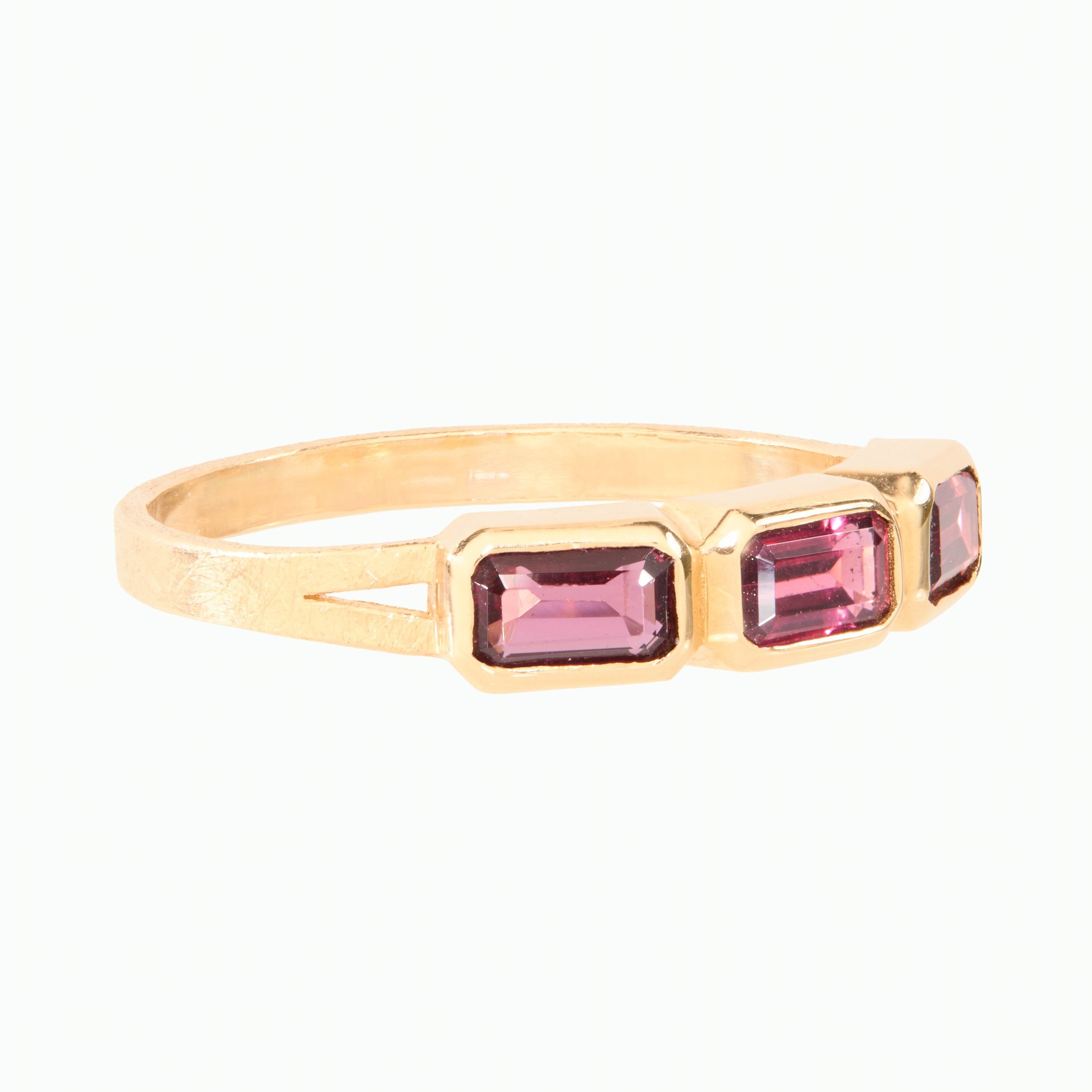 Gold ring with purple gemstones on a white background