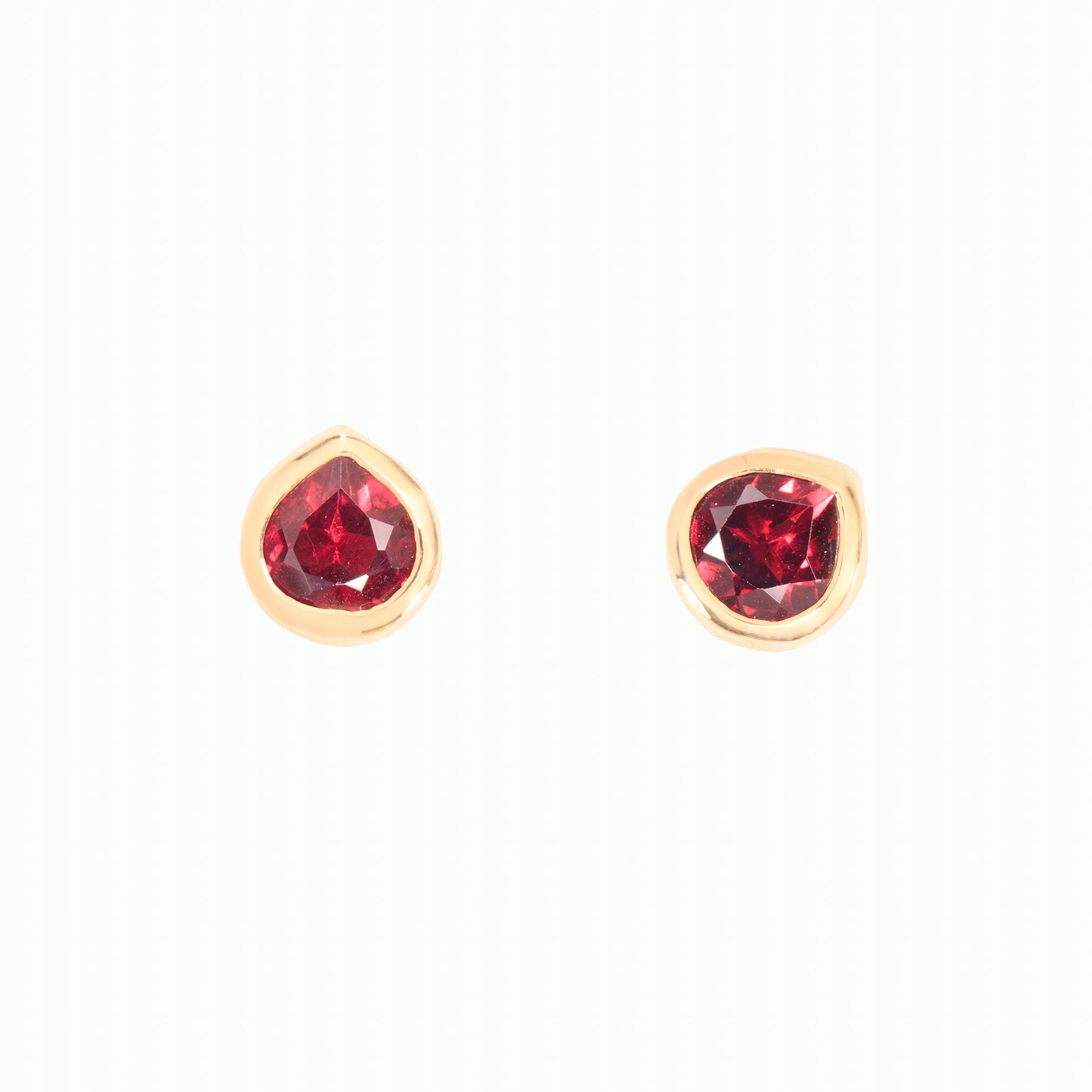 Pair of gold earrings with red gemstones on a white background