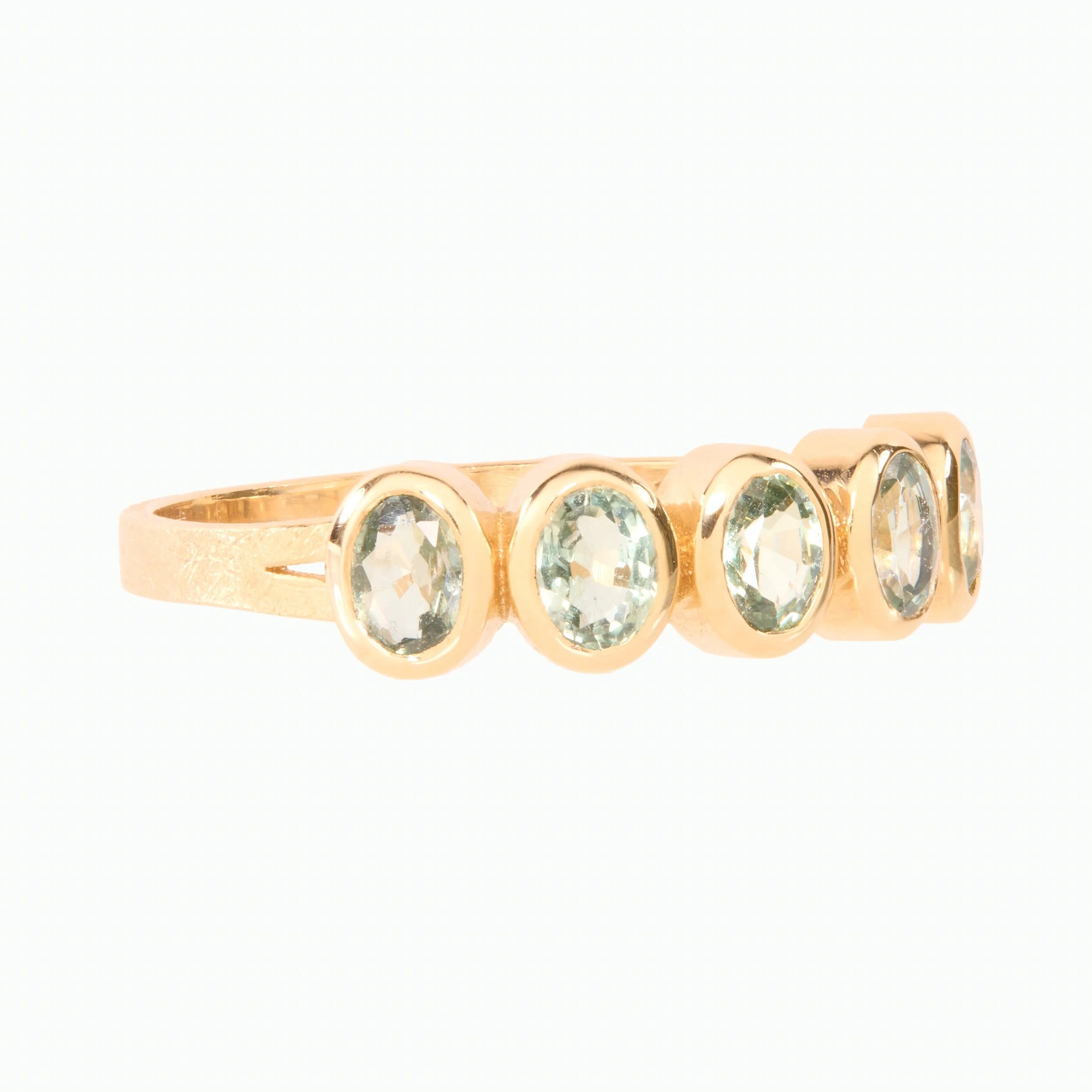 Gold ring with green oval gemstones on a white background