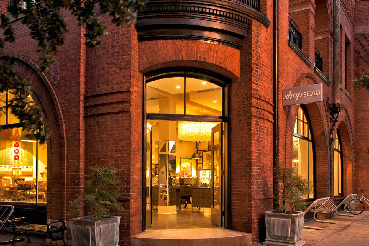 Brick building with large glass windows at night, illuminated by interior lights.